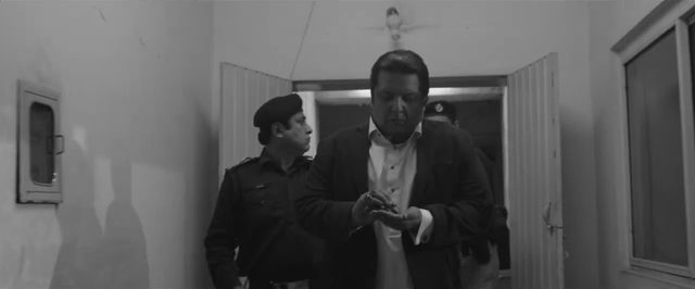 Still from Driven (2015), directed by Michael S.U. Hudson: a businessman followed by police officers along a corridor at night