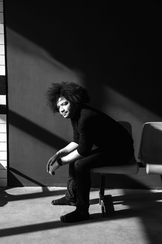 Michael S.U. Hudson, Creator, seated in raking light, black and white